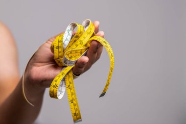 Bir el, kişisel gelişimin ve kendini geliştirmenin karmaşıklığını sembolize eden karışık bir mezura tutuyor..