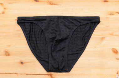 Şık bir siyah bikini iç çamaşırı, temiz çizgiler ve minimalizmi vurgulayan ahşap bir yüzey sergiliyordu..