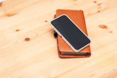 Bir cep telefonu ahşap bir masanın üzerinde bir cüzdan dinlenir ve sıradan bir yaşam tarzını yakalar..