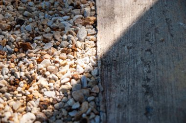 Doğanın dokusunu vurgulayan beton bir sınırla çakıllı bir patikanın ayrıntılı bir görüntüsü.