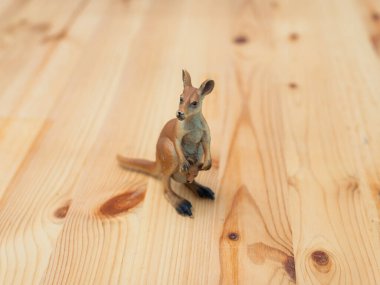 Ahşap bir yüzeyi dinlendiren kanguru oyuncağı figürünün neşeli özünü detaylı bir şekilde yansıtması..
