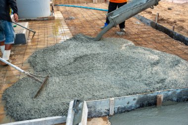 İşçiler, kritik inşaat tekniklerini gösteren sağlam temeller oluşturmak için beton döküyorlar..