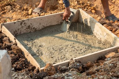 Beton döken bir işçinin yakın çekim görüntüsü inşaat sürecini eylem halinde gösteriyor.