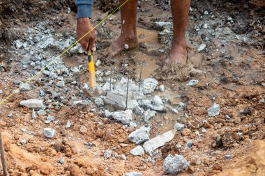 Bir işçi bir kazı sahasında moloz kazıyor ve inşaatta çok çalıştığını gösteriyor..