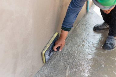 A construction worker skillfully applies a concrete finish in a residential area showcasing craftsmanship.