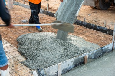 İşçiler bir inşaat sahasına ustalıkla beton dökerek şehir sanayi ortamında takım çalışması yapıyorlar..