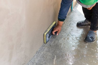 Becerikli bir işçi, açık hava inşaat alanındaki yeni dökülmüş betona son rötuşları uygular..