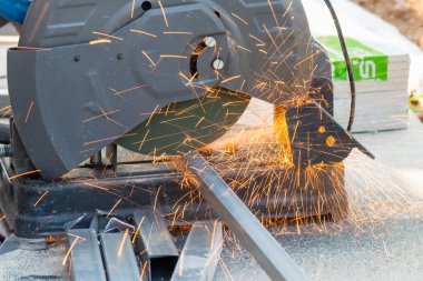 Bir zanaatkar, yoğun bir atölyede ustalıkla metal kıvılcımları kesiyor..