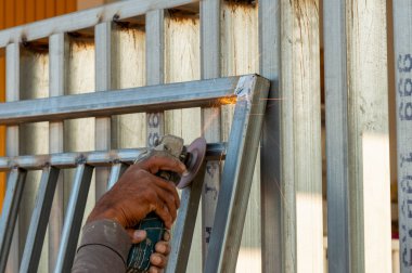 Yetenekli bir işçi, endüstriyel bir atölyede metal kaynaklamak için öğütücü kullanır..