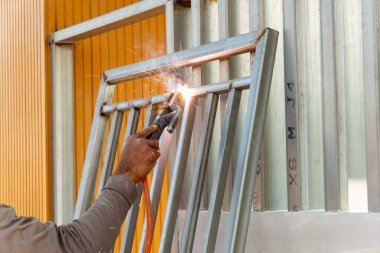 Yetenekli bir işçi, endüstriyel bir atölyede metal kaynaklıyor ve ustalık ve hassasiyet gösteriyor..