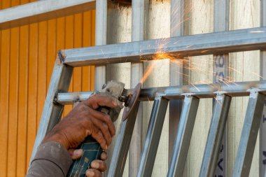 Yetenekli bir işçi, bir atölyede metal işçiliğini kesmek için öğütücü kullanır..