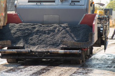 Bir yol yapım ekibi şehir altyapısını geliştirmek için taze asfalt uygular.