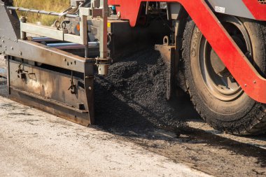 Ağır makineler asfalt döşeyerek kentsel altyapı gelişimini gösteren bir inşaat sahası oluşturuyor.
