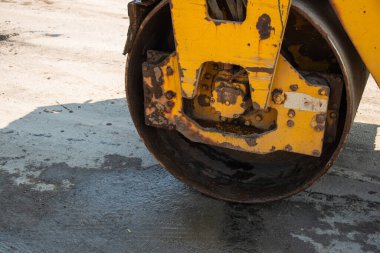 Hareketli bir şehir ortamında tekerleklerini yassılaştıran bir buharlı silindirin yakın çekimi..