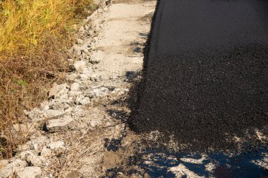 Bu resim, yol yapım sürecini vurgulayan kentsel bir ayarda asfalt katman işlemini yakalar.