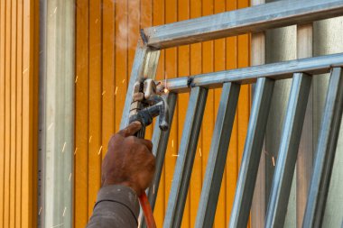 Yetenekli bir işçi, canlı bir endüstriyel atölyede metal yapıları ustalıkla kaynak yapar..