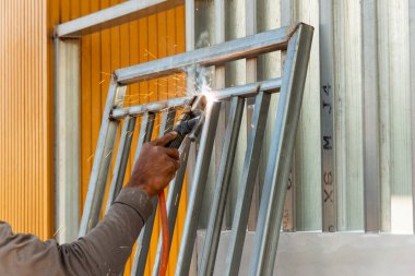 Yetenekli bir işçi, bir endüstriyel atölyede ustalıkla metal bir çerçeve kaynatıyor..