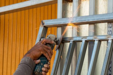 Bir zanaatkar, metali ustalıkla öğütücüyle keser ve canlı bir atölyede kıvılcımlar yaratır..