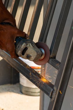 Yetenekli bir işçi, canlı bir endüstriyel ortamda metal sergilenen kıvılcımları şekillendirmek için öğütücü kullanır..