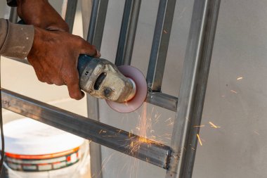 Bir zanaatkar, endüstriyel atölyede kıvılcımlar yaratan bir metali ustaca öğütür..