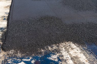 İnşaat sürecini gösteren kentsel yollarda sergilenen taze asfalta ayrıntılı bir bakış.