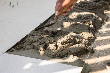 Bir inşaat işçisi, evin tadilatı sırasında yer döşemeleri için ustalıkla çimento döşeyebilir..