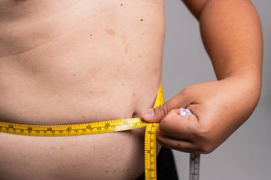 Bir insan, kişisel bakım ve farkındalığı vurgulayan sağlık anlayışına göre belini ölçer..