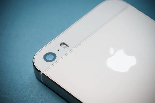 El iPhone de Apple de oro 5s sobre fondo de papel azul Imágenes de stock libres de derechos
