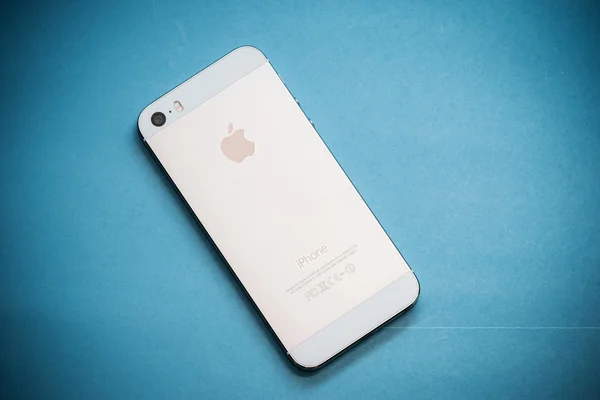 El iPhone de Apple de oro 5s sobre fondo de papel azul — Foto de Stock