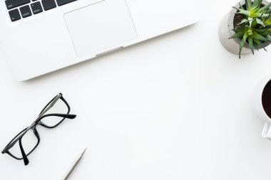 Laptop bilgisayar ve ofis malzemeleriyle dolu beyaz ofis masası. Kopyalama alanı olan üst görünüm, düz yatay.