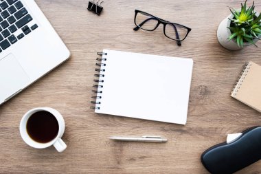 Kalem ve malzemelerle dolu boş defter defterli ahşap ofis masası. Kopyalama alanı olan üst görünüm, düz yatay.