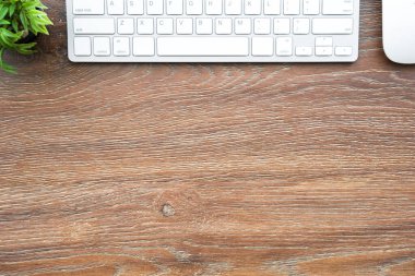 Bilgisayar faresi ve klavyeli ahşap ofis masası. Kopyalama alanı olan üst görünüm, düz yatay.