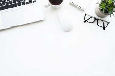 Üzerinde dizüstü bilgisayar ve bir sürü malzeme olan beyaz ofis masası. Kopyalama alanı olan üst görünüm, düz yatay.