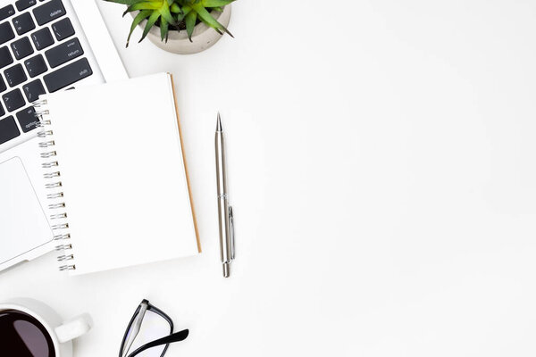 Бланк небольшой страницы ноутбука находится на верхней части белого стола офиса стол с ручкой, ноутбуком и принадлежностями. Вид сверху с копировальным пространством, плоская кладка.