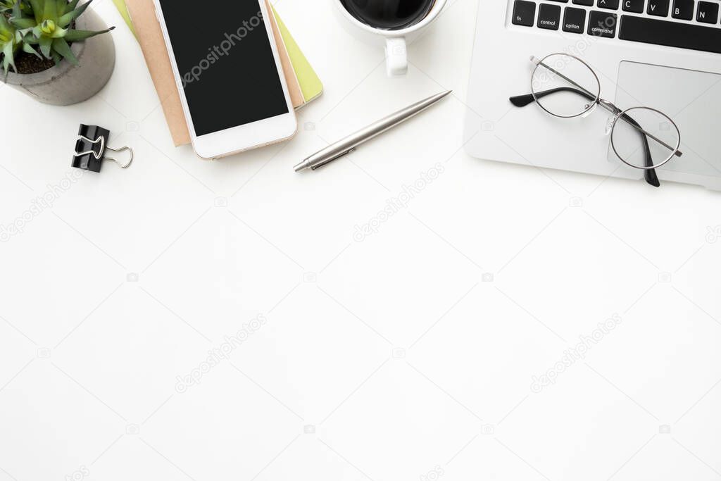 White office desk table with smartphone, laptop computer and supplies. Top view with copy space, flat lay.