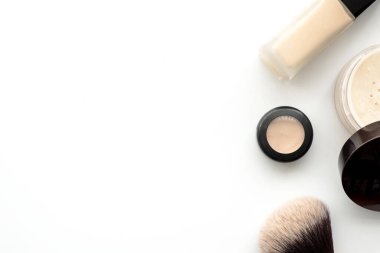 Temeli, pudrası, kapatıcı ve fırçayla makyaj seti. Kopyalama alanı olan üst görünüm, düz yatay.