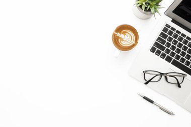 Laptop bilgisayarı, kahve, kalem ve gözlüklü beyaz ofis masası. Kopyalama alanı olan üst görünüm, düz yatay.