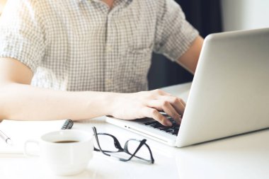 Genç adam dizüstü bilgisayar klavyesinde yazıyor. İnternet öğrenimi, sörf konsepti.