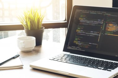 Ahşap yazılım geliştiricisi veya programcı ofis masası üzerinde yazılım kodu olan dizüstü bilgisayarlı.