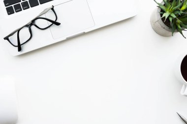 İçinde dizüstü bilgisayar ve bir sürü malzeme olan beyaz ofis masası. Kopyalama alanı olan üst görünüm, düz yatay.