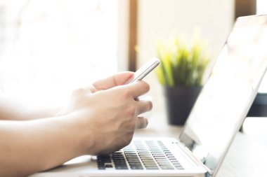 Adam dizüstü bilgisayarda akıllı telefon kullanıyor. Çevrimiçi teknoloji kavramına sahip yaşam.