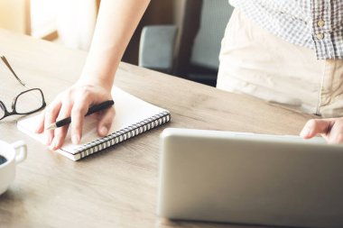 Genç adam dizüstü bilgisayarını kullanarak internet araştırmalarından bir not alıyor. Teknoloji konseptiyle öğrenme.