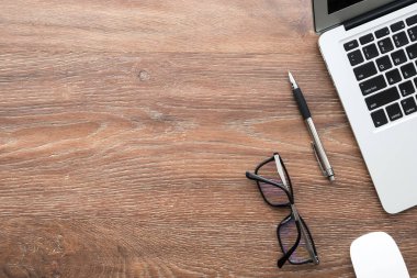 Laptop bilgisayar ve malzemelerle dolu ahşap ofis masası. Kopyalama alanı olan üst görünüm, düz yatay.