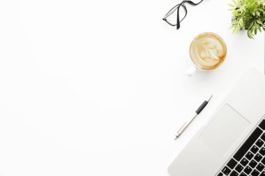 Laptop bilgisayarı, kahve, kalem ve gözlüklü beyaz ofis masası. Kopyalama alanı olan üst görünüm, düz yatay.