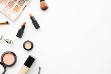 Güzellik kozmetiğinin düz bir görüntüsü ruj, göz farı paleti, allık, kapatıcı, fondöten ve fırçalarla yapılmış. Metnin için kopyalama alanı olan en üstteki görünüm.