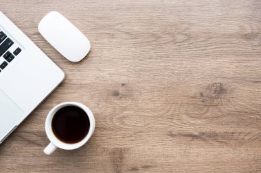 Minimalist ahşap ofis masası, dizüstü bilgisayarlı kahve ve kablosuz fare. Kopyalama alanı olan üst görünüm, düz yatay.