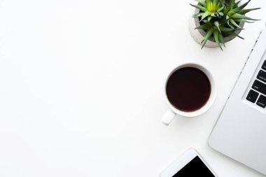 Laptop bilgisayarlı beyaz ofis masası, bir fincan kahve ve akıllı telefon. Kopyalama alanı olan üst görünüm, düz yatay.