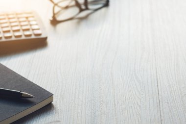 Ahşap ofis hesap makinesiyle çalışma masası, kalem ve gözlüklü defter. Metnin için boşluk kopyala.
