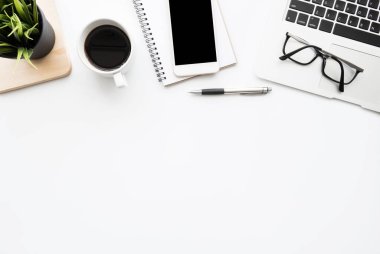 Akıllı telefonlu beyaz ofis masası boş ekran, dizüstü bilgisayar, bir fincan kahve ve malzeme. Kopyalama alanı olan üst görünüm, düz yatay.