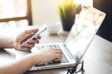 Adam bilgisayarda akıllı telefondan gelen bilgilerle bir şeyler yazıyor. Çevrimiçi cep telefonu ödeme kavramı.